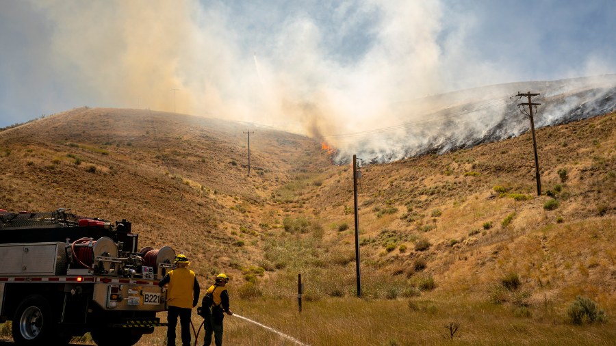 Image: Firefighters prepare to battle a new fire that started near the Manastash Vista Point along ...
